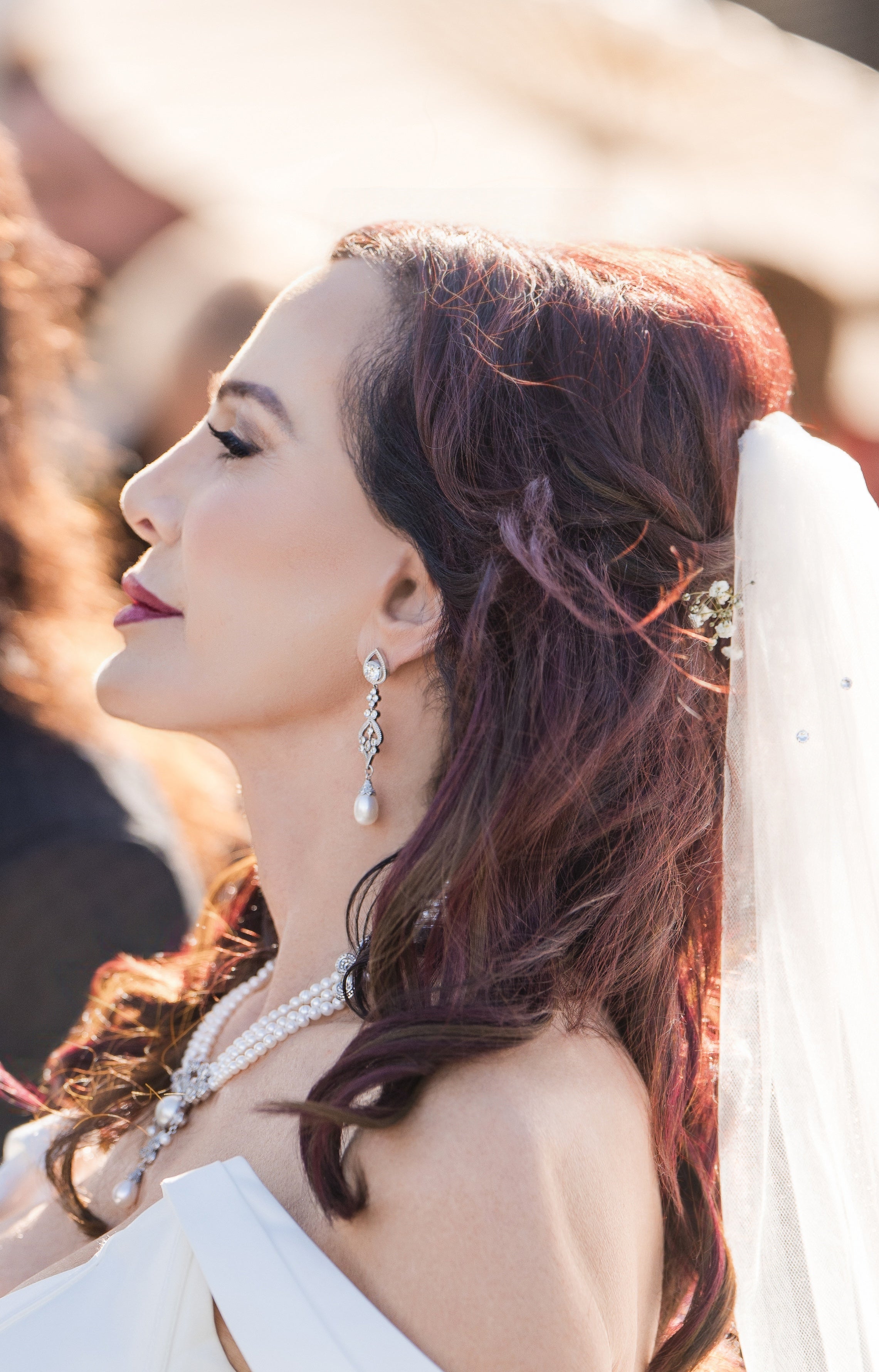 Sheryl Cooper in a wedding dress with a veil and jewelry, outdoors.