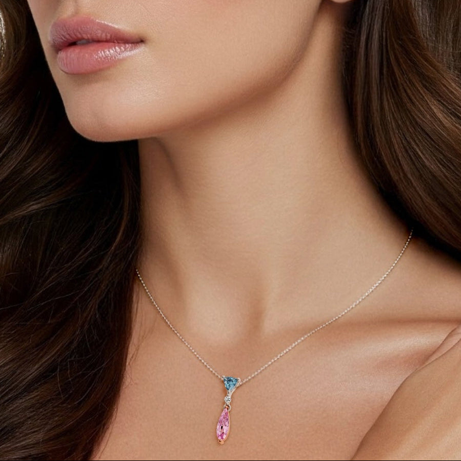 Woman wearing a delicate necklace with a clear stone and pink gemstone against a neutral background